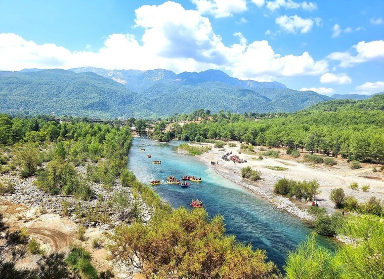A river with boats, surrounded by mountains and trees. 5