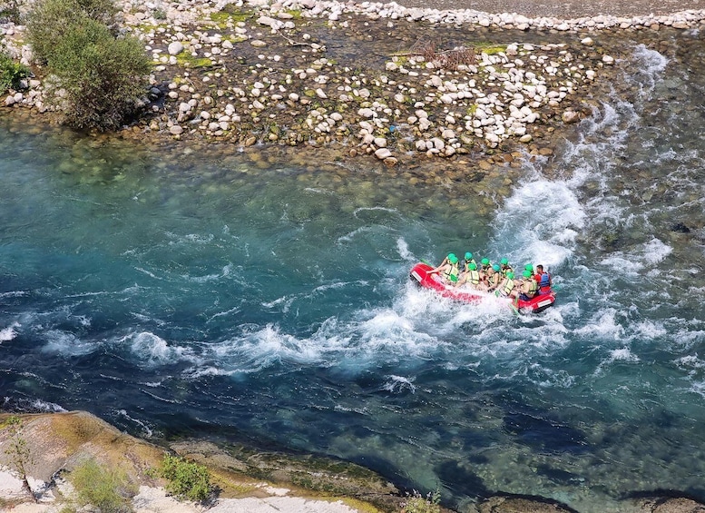 A group of people rafting down a river surrounded by rocks and greenery. 2