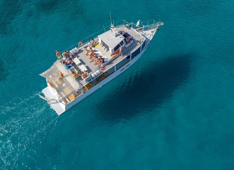 A white yacht with a deck full of people, surrounded by turquoise water. 2
