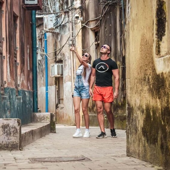 Two people standing in an alleyway with a building on one side and a utility pole on the other. 1