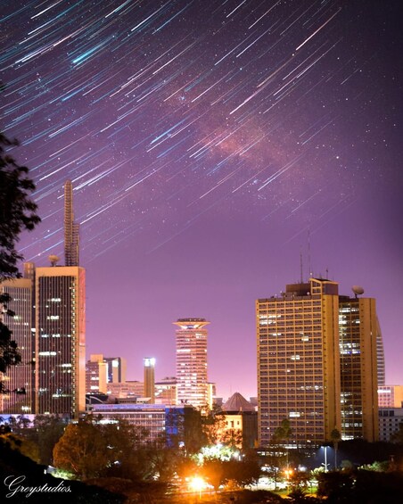 A city skyline at night with star trails in the sky. 2