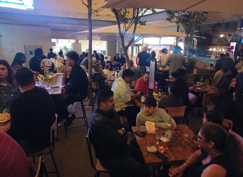 A crowded outdoor dining area with people seated at tables. 4