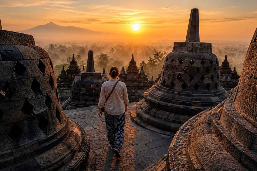 A person walking between ancient stone structures during sunrise. 1