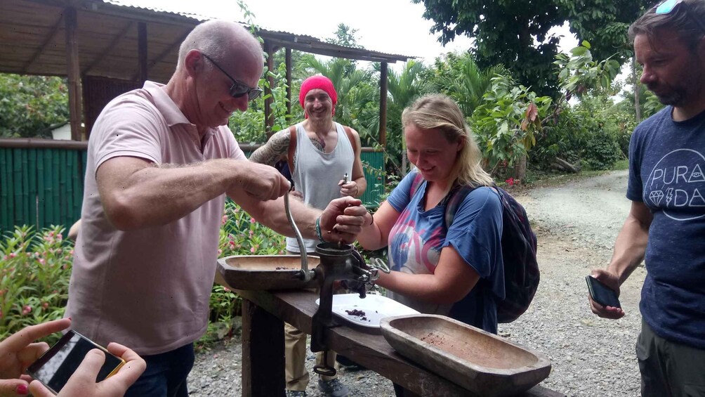 A group of people around a traditional coffee grinder. 5