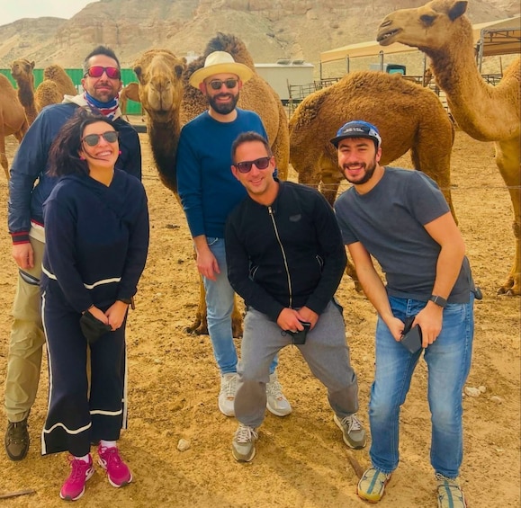 A group of people with camels in a desert setting. 2