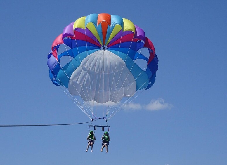 Two people skydiving with a multicolored parachute. 4
