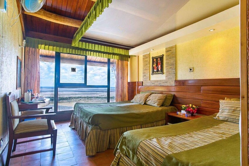 A room with two beds, a desk, a chair, and a window with a view. 5