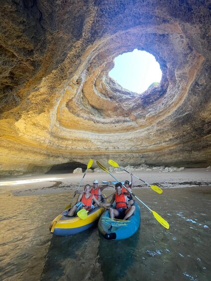 Two people kayaking in a cave with a large circular rock formation in the background. 5