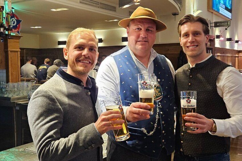 Three people holding glasses of beer in a bar setting. 2