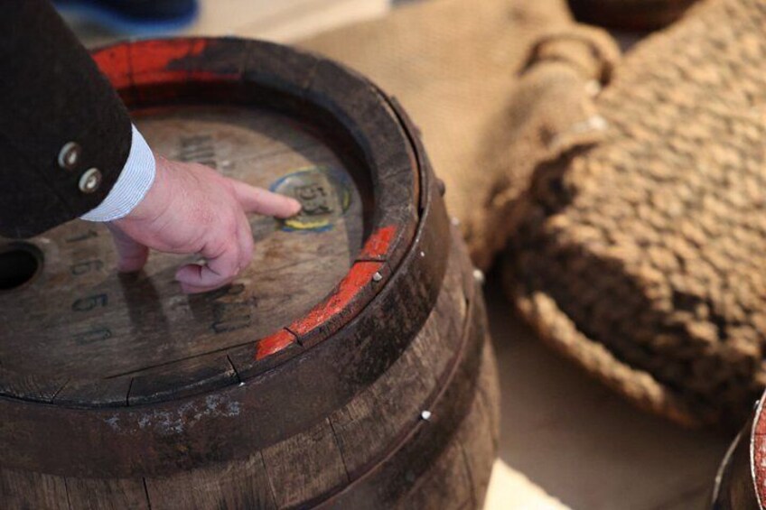 A wooden barrel with a hand pointing at a label. 5