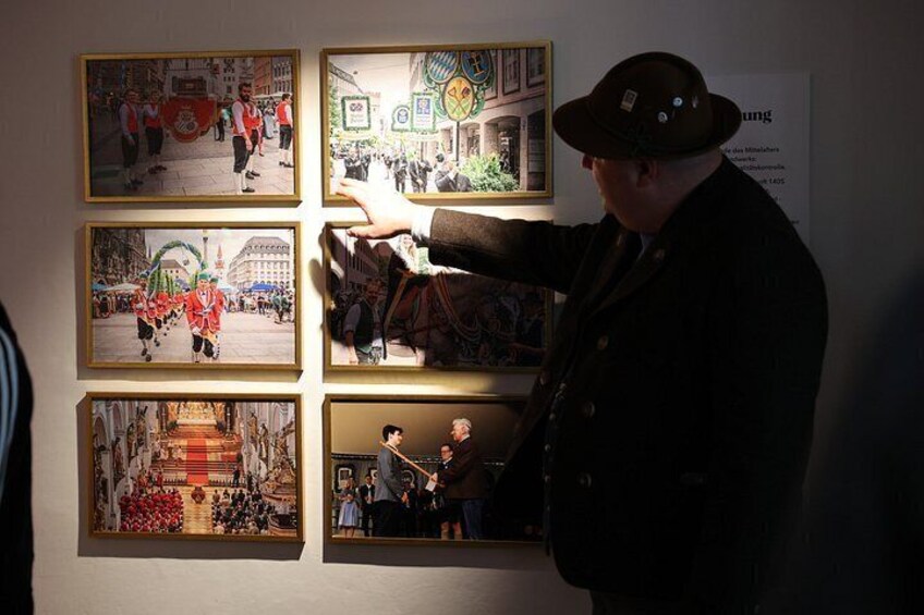 A person pointing at a wall with six framed pictures. 4