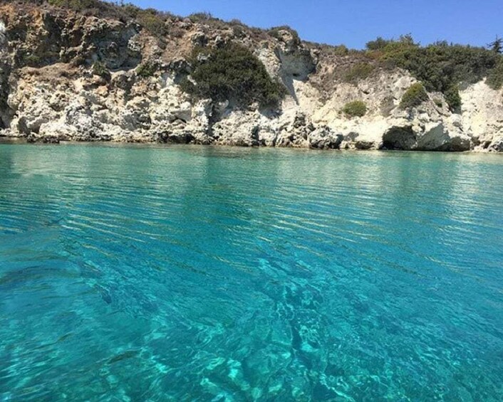 A clear turquoise sea with rocky cliffs in the background. 3