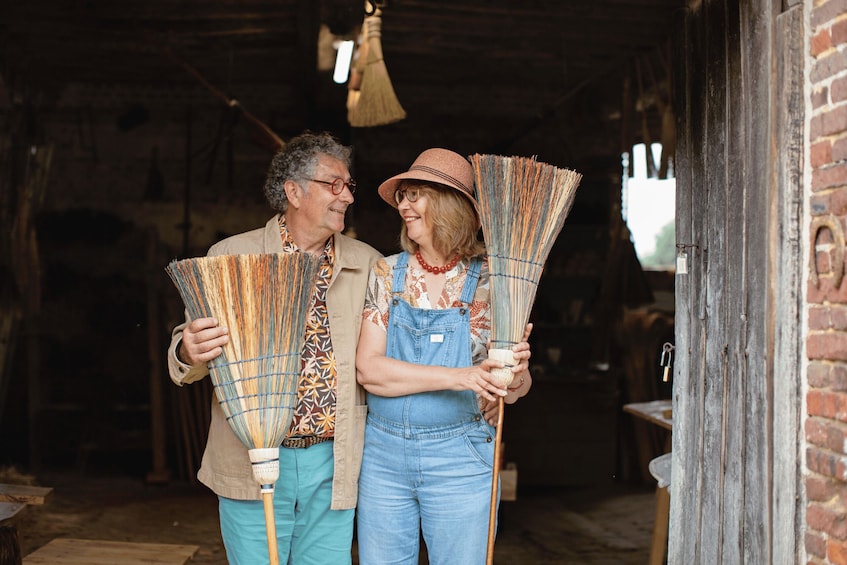 Two people holding brooms inside a rustic barn. 5