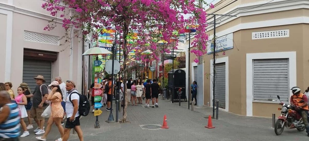 A busy street with pedestrians, a motorcycle, and colorful umbrellas. 2