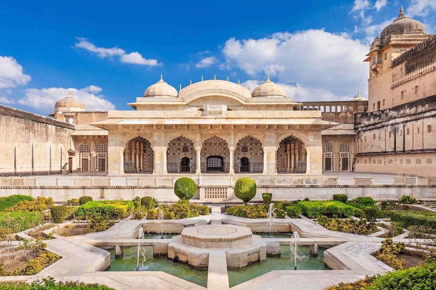 A historic building with domed architecture, a central water feature, and well-manicured gardens. 1