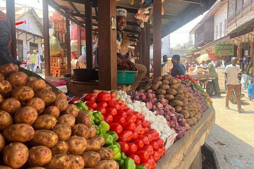 Un étal de marché où l’on vend des pommes de terre, des poivrons rouges et verts, et des aubergines violettes. 5