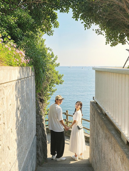 A couple holding hands on a stone staircase overlooking a body of water with boats. 5