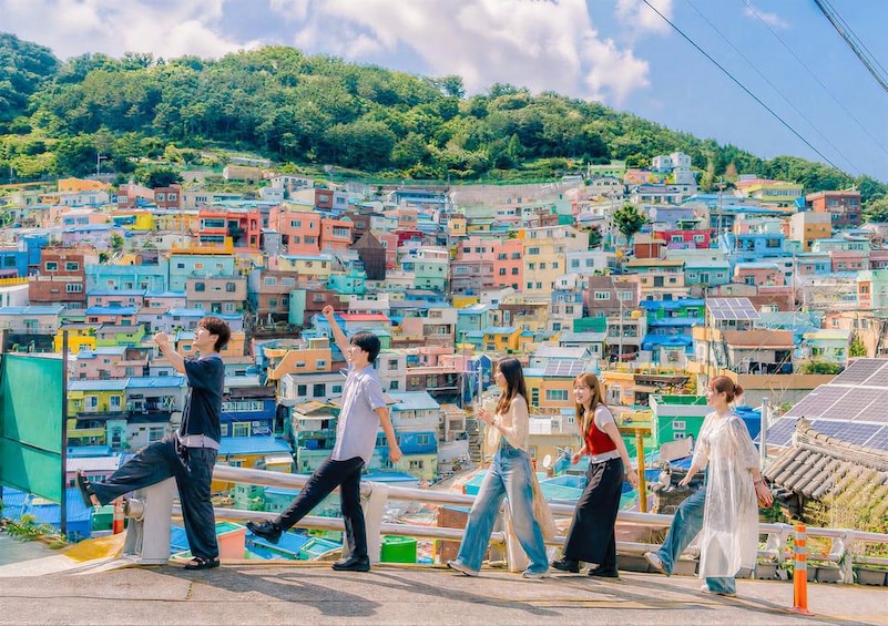 A group of people walking on a bridge with colorful buildings in the background. 3