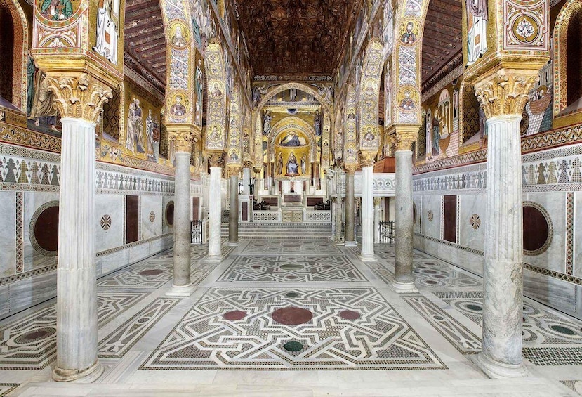An ornate interior with intricate mosaics, columns, and a central altar. 1