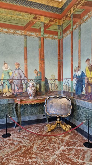 A historical mural with figures in traditional attire, a decorative table, and a golden lion statue. 3