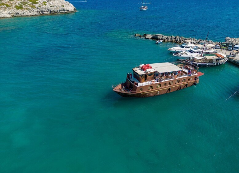 A large boat docked at a pier with several smaller boats nearby. 4