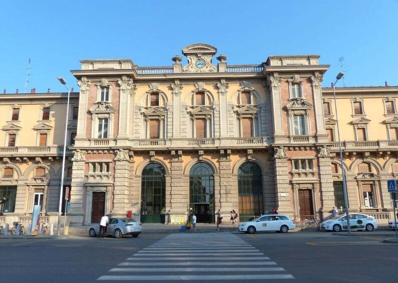 A historic building with classical architecture, large arched windows, and a central clock. 1