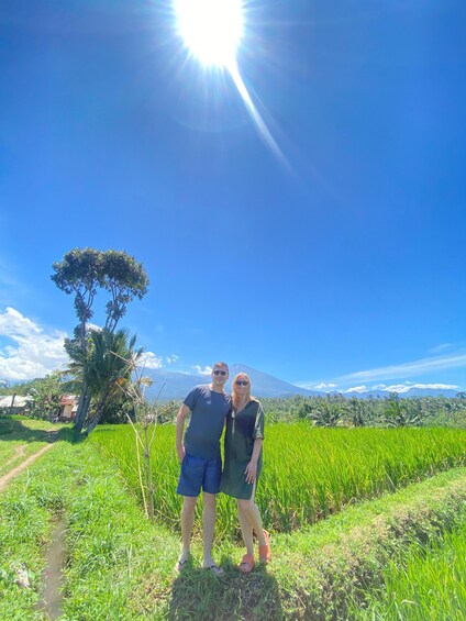 Two people standing in a field with a mountain in the background. 1