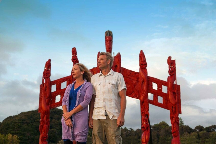 Two people standing in front of a red sculpture. 2