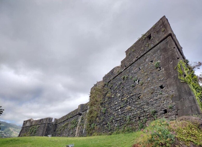 A large stone fortress with a grassy foreground and cloudy sky. 4