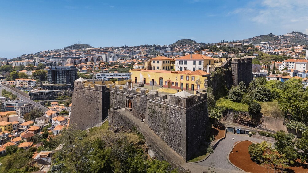 A historic fort overlooking a city with terraced houses and modern buildings. 1