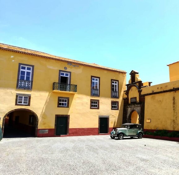 A yellow building with a vintage car parked in front. 3