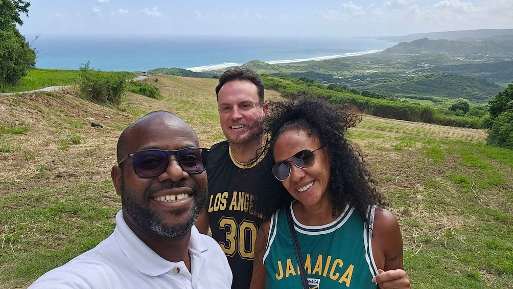 Three people posing with a scenic view of a coastal landscape. 4