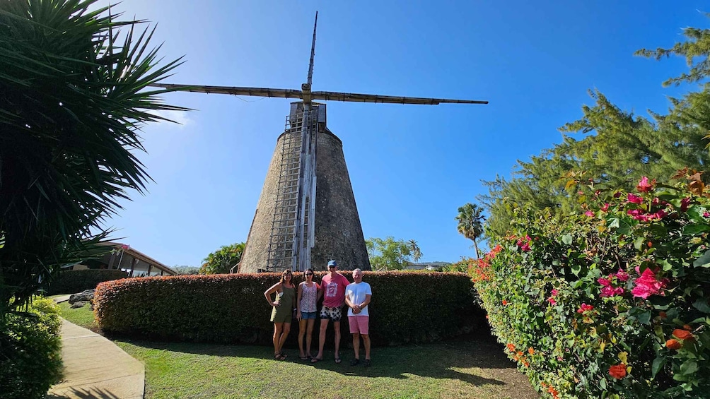 A group of people standing in front of a windmill. 1