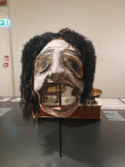 A wooden mask with a black wig on display. 5