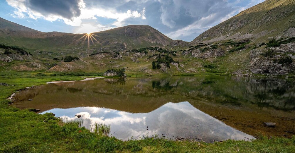 A mountain landscape with a lake reflecting the sky and sun. 4