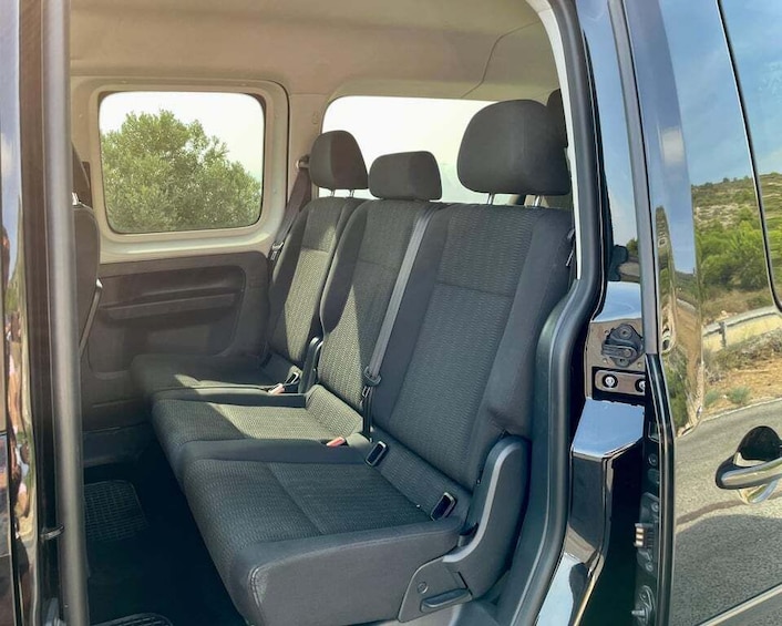 A van interior with two rows of seats, a rearview mirror, and a window. 1