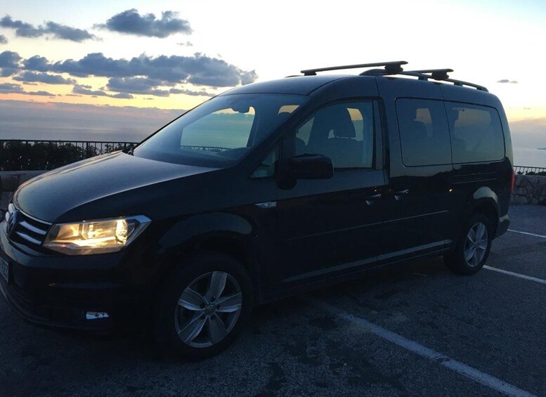 A black van parked on a road with a sunset in the background. 3