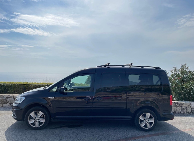 A black SUV parked outdoors with a stone wall and greenery in the background. 2