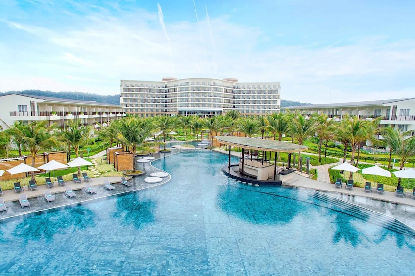 A resort with a central pool, palm trees, and a large hotel building. 2