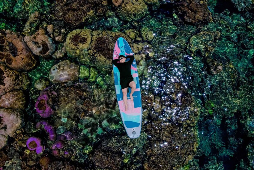 A person lying on a surfboard on a rocky underwater surface. 4