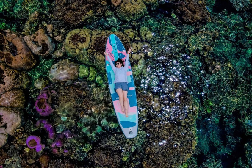 A person lying on a surfboard on a rocky underwater surface. 1