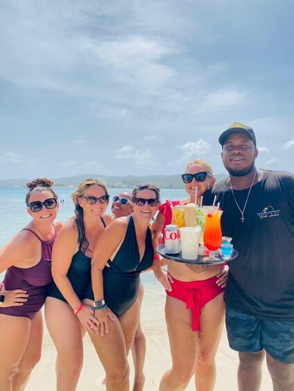 A group of people on a beach with drinks and a tray. 2