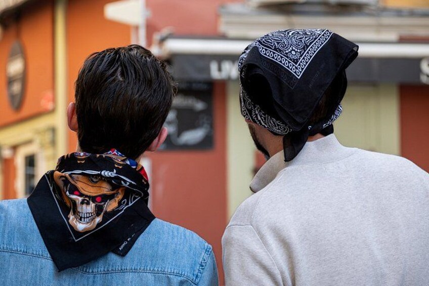 Zwei Personen von hinten zu sehen, eine trägt eine Jeansjacke, die andere ein weißes Hemd, beide mit einem gemusterten Schal um den Hals. 4