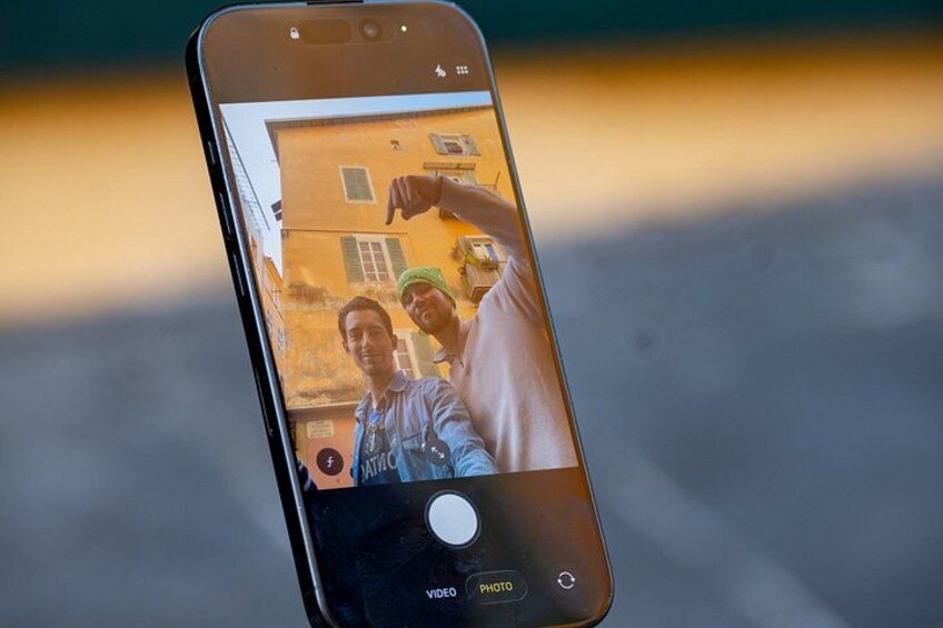 Ein Smartphone, das ein Foto von zwei Personen vor einem Gebäude zeigt. 3