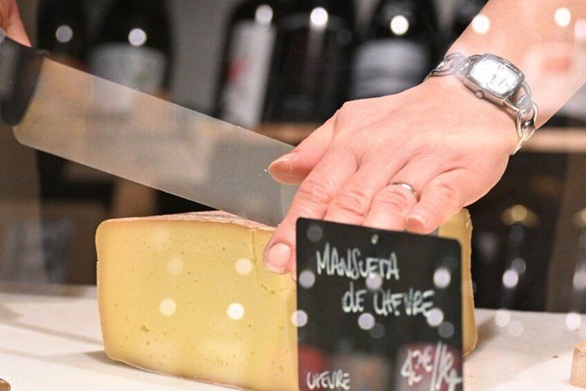 A person cutting a large block of cheese with a knife. 2