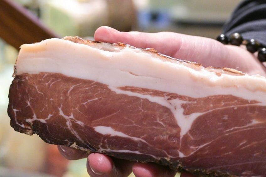 A hand holding a piece of meat with a layer of fat on top. 4