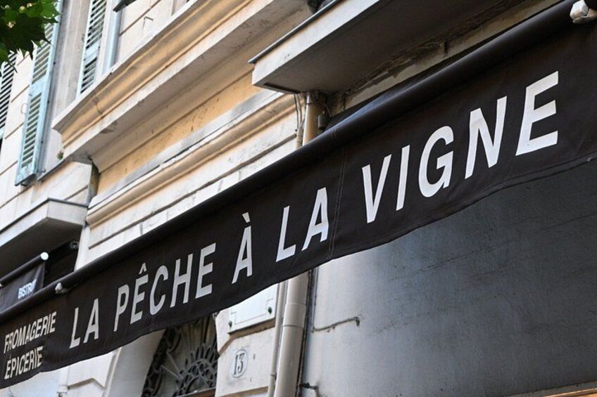 A street sign with the text 'LA PÉCHE À LA VIGNE' and 'FROMAGERIE EPICERIE' indicating a cheese shop. 3