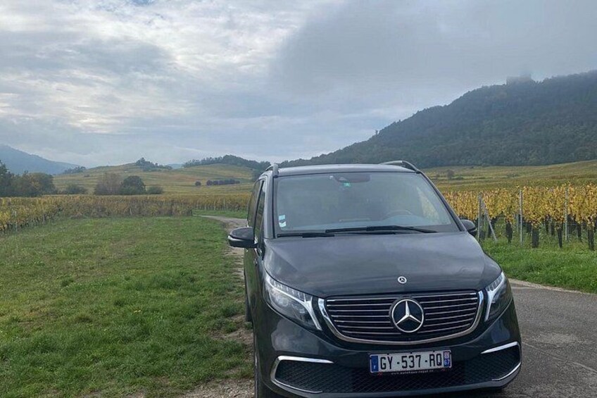 A black Mercedes-Benz SUV parked on a rural road with vineyards in the background. 1