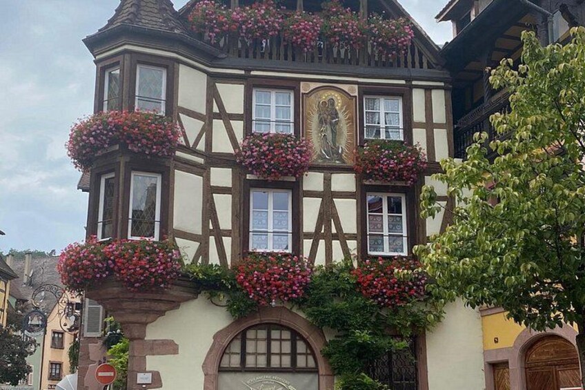 A half-timbered building with flower boxes and a statue. 4