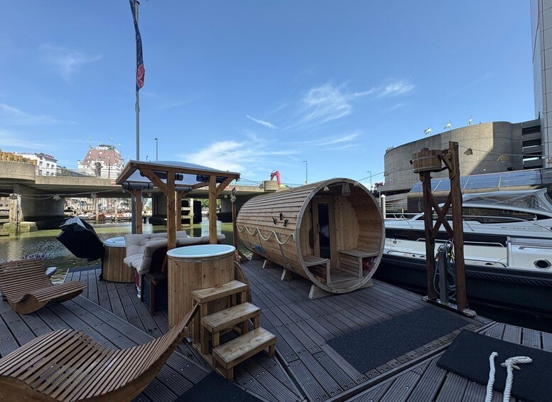A wooden deck with a sauna, outdoor seating, and a view of the water and buildings. 5